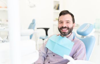 Happy mature man with a perfect smile sitting in a dental chair.