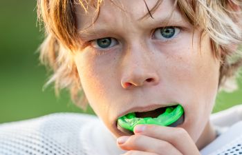 A teenage boy putting a mouthguard in his mouth before playing rugby.