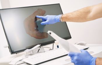 Dentist revising dental imaging and explaining dental treatment to a patient.