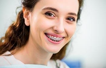 A broadly smiling woman wearing orthodontic braces.