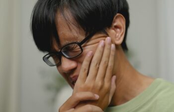 Asian man in severe toothache checking teeth with phone camera.